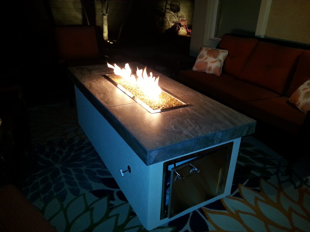 Fire table burning at night on a Las Vegas patio, built by Sun West Outdoor Kitchens