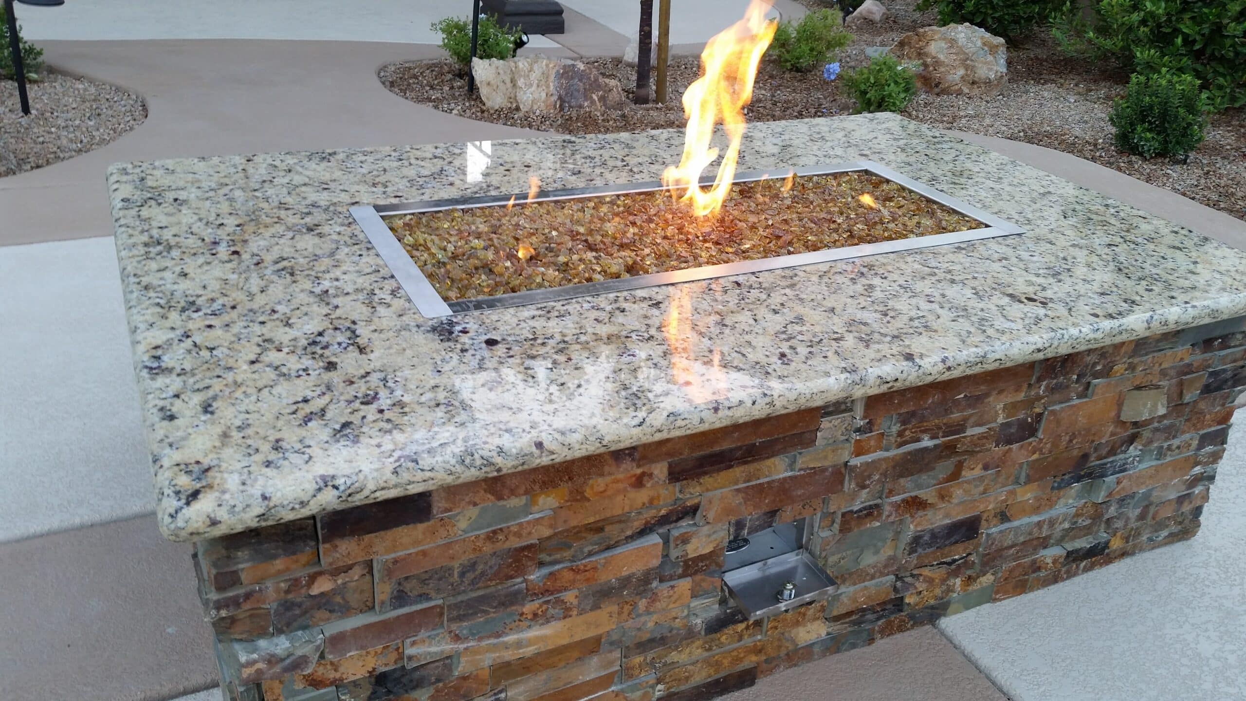 Custom stacked-stone fire pit with fire glass in a Las Vegas backyard