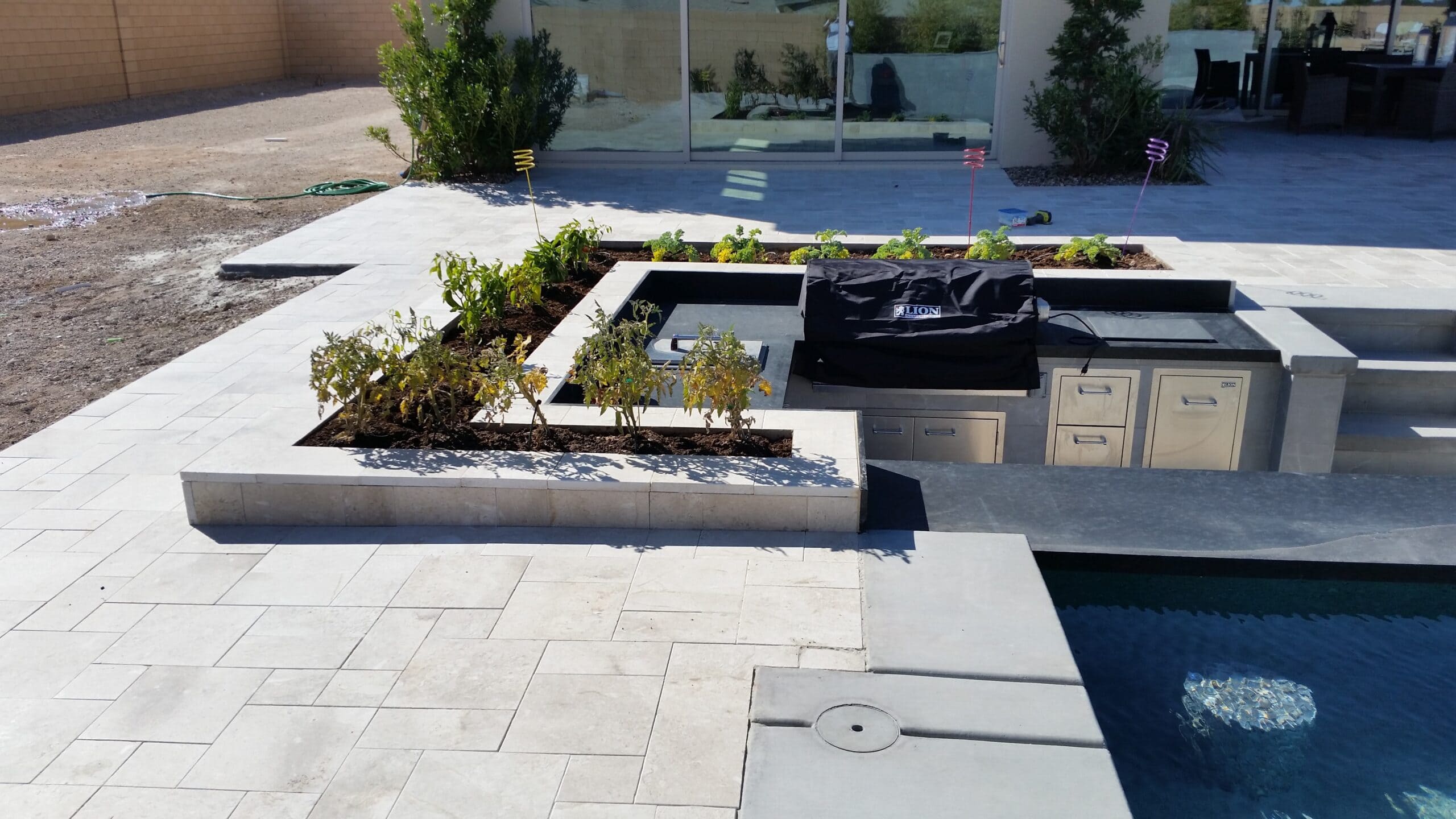 Modern poolside outdoor kitchen with built-in planters in Las Vegas