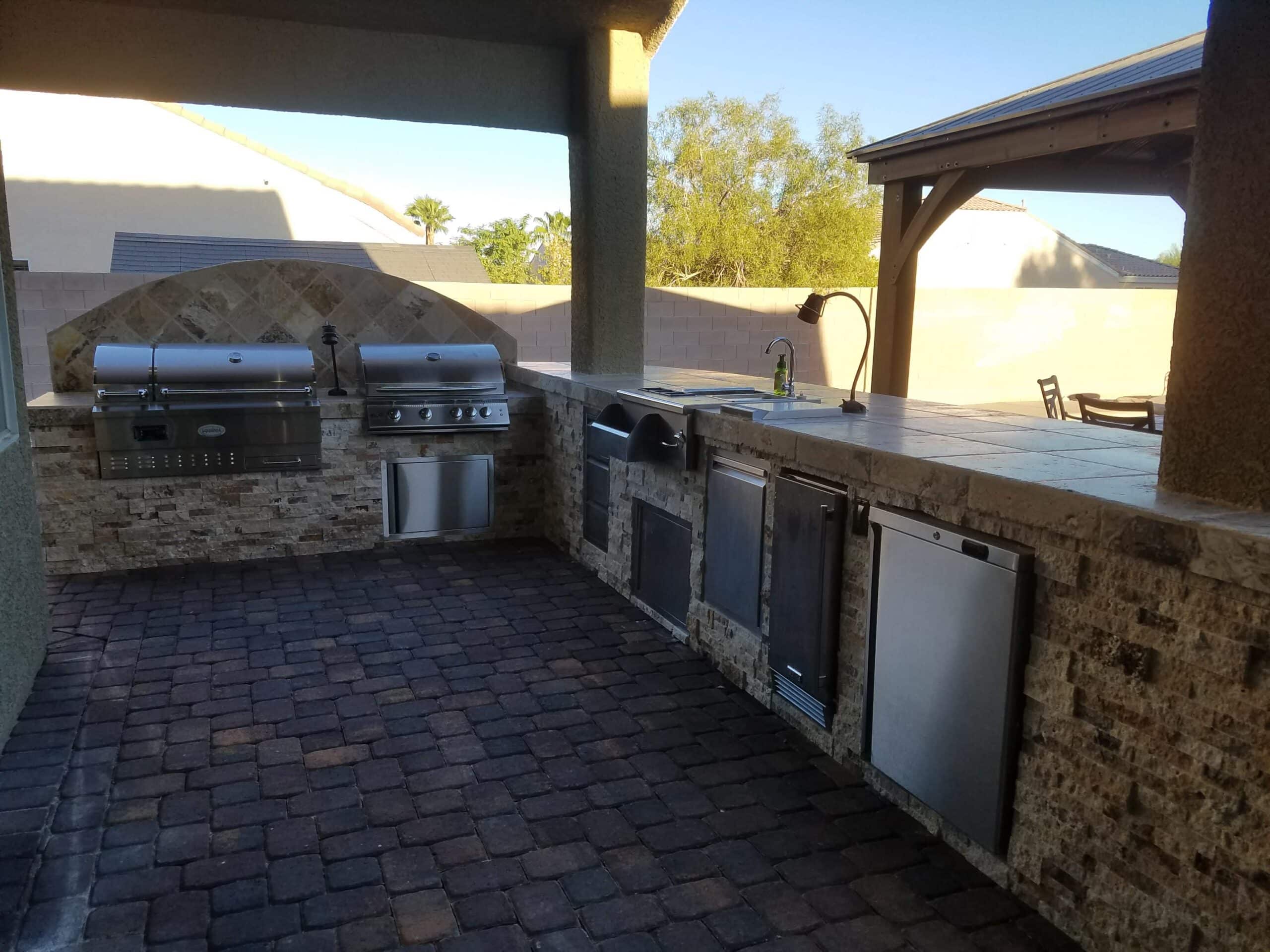Covered outdoor kitchen with arched design, grill and refrigerator in Las Vegas
