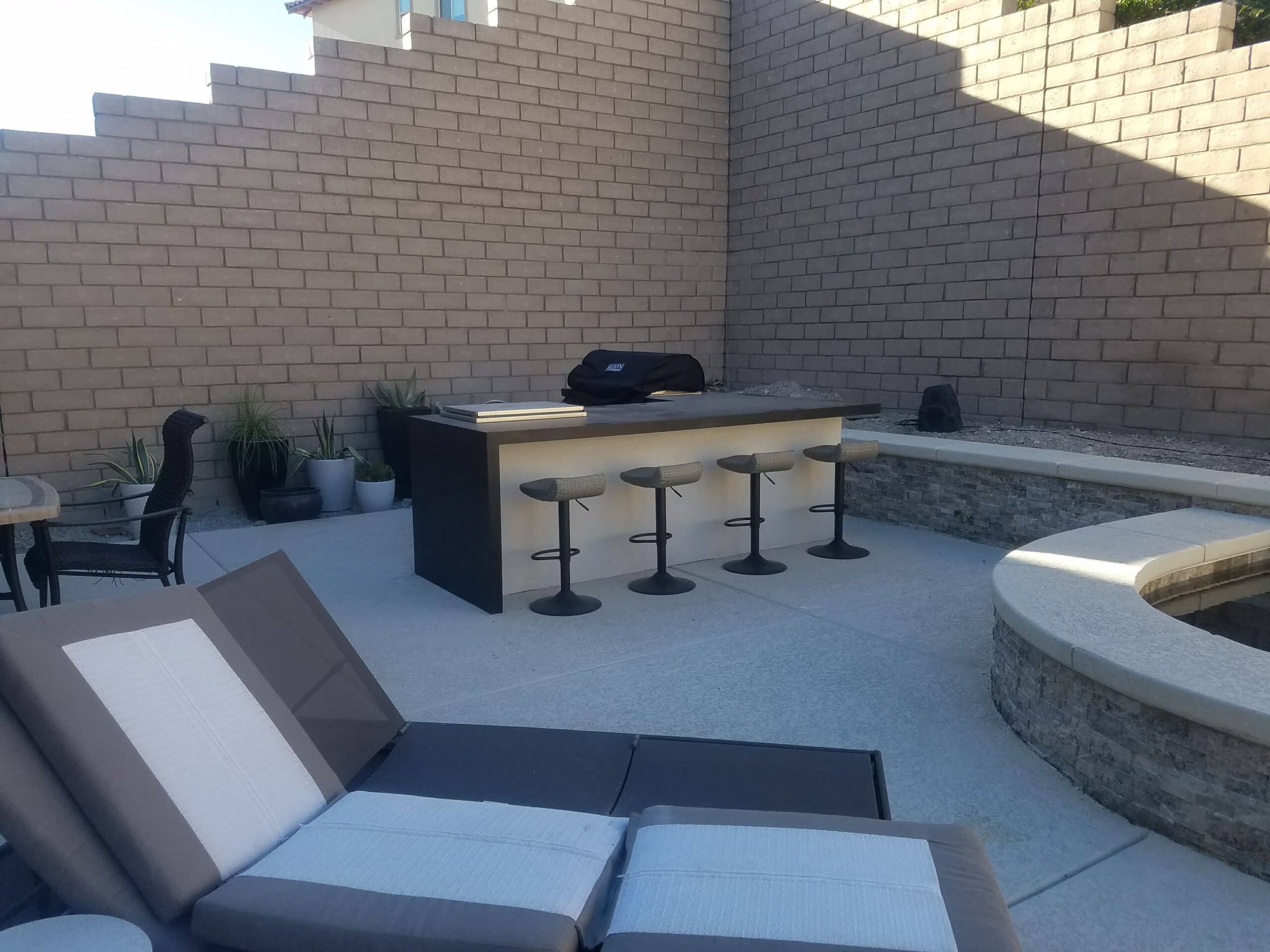 BBQ island with bar stools and curved seat wall in a Las Vegas backyard