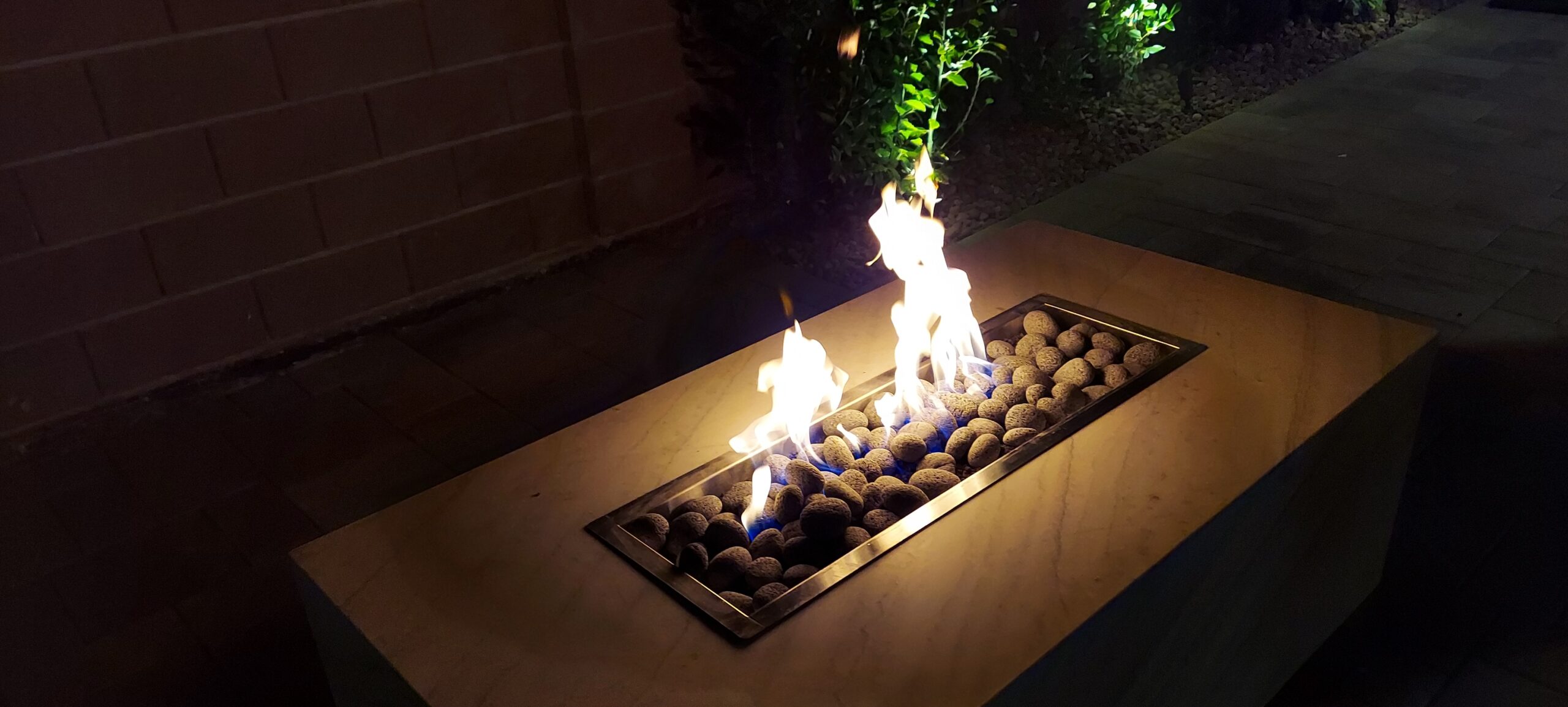 Custom linear fire pit lit at night in a Las Vegas backyard