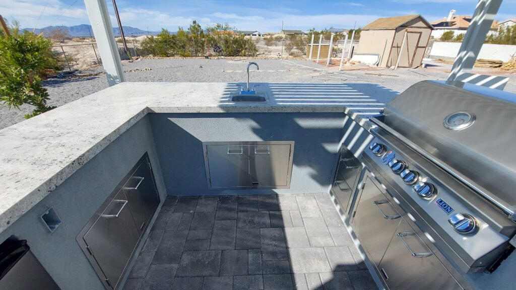 L-shaped outdoor kitchen with pergola shade structure in a Summerlin-area backyard