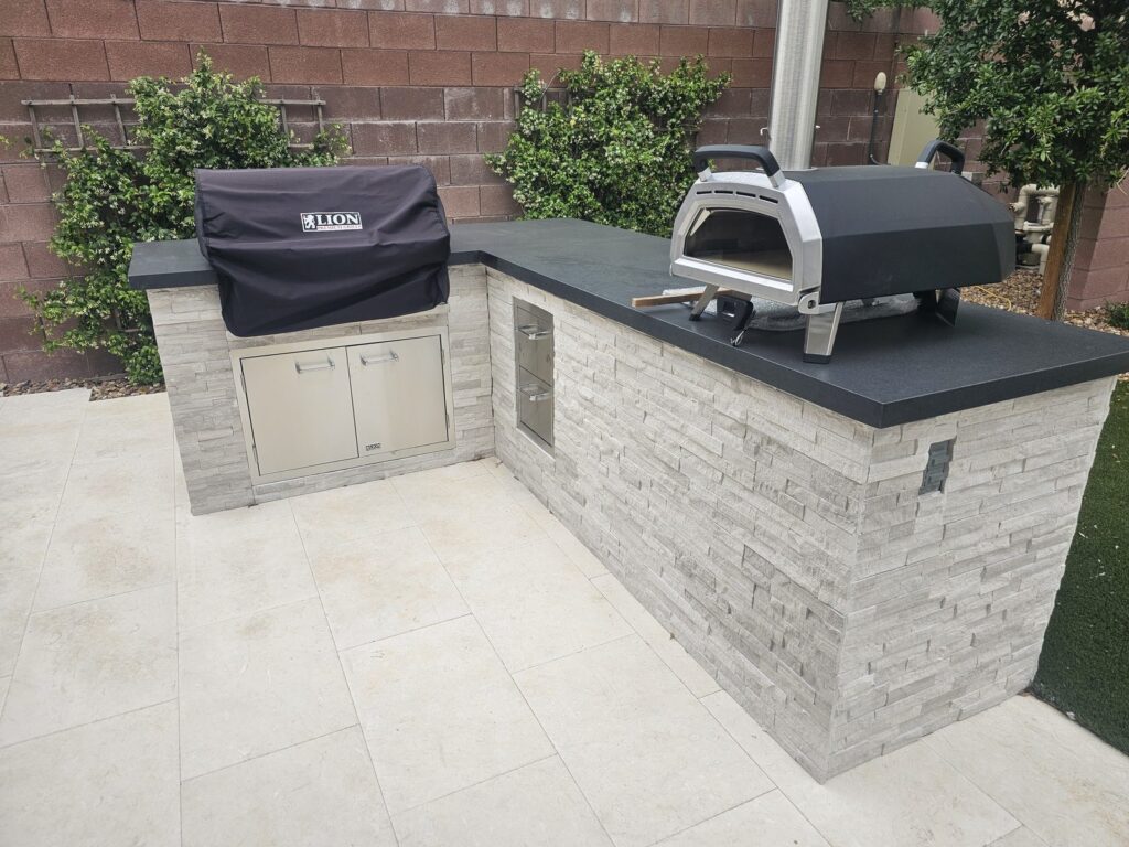 L-shaped BBQ island with black granite counter, Ooni pizza oven and Lion grill in Seven Hills, Henderson