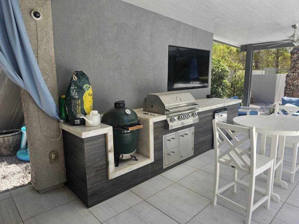 Finished outdoor kitchen with flush-mount TV media wall, Big Green Egg and Lion grill in Southern Highlands