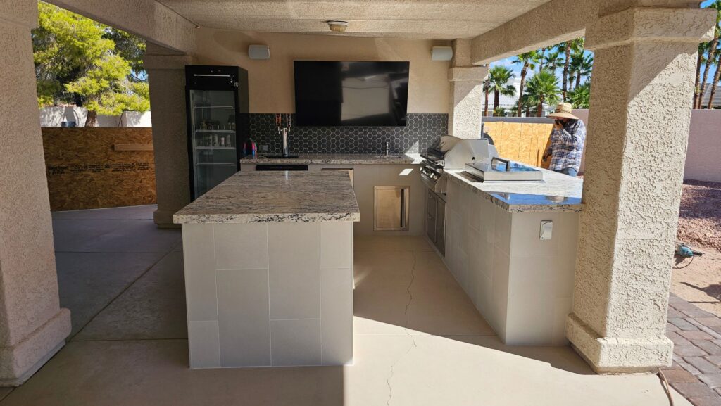 Finished L-shaped outdoor kitchen with granite island and bar seating in Lone Mountain Las Vegas