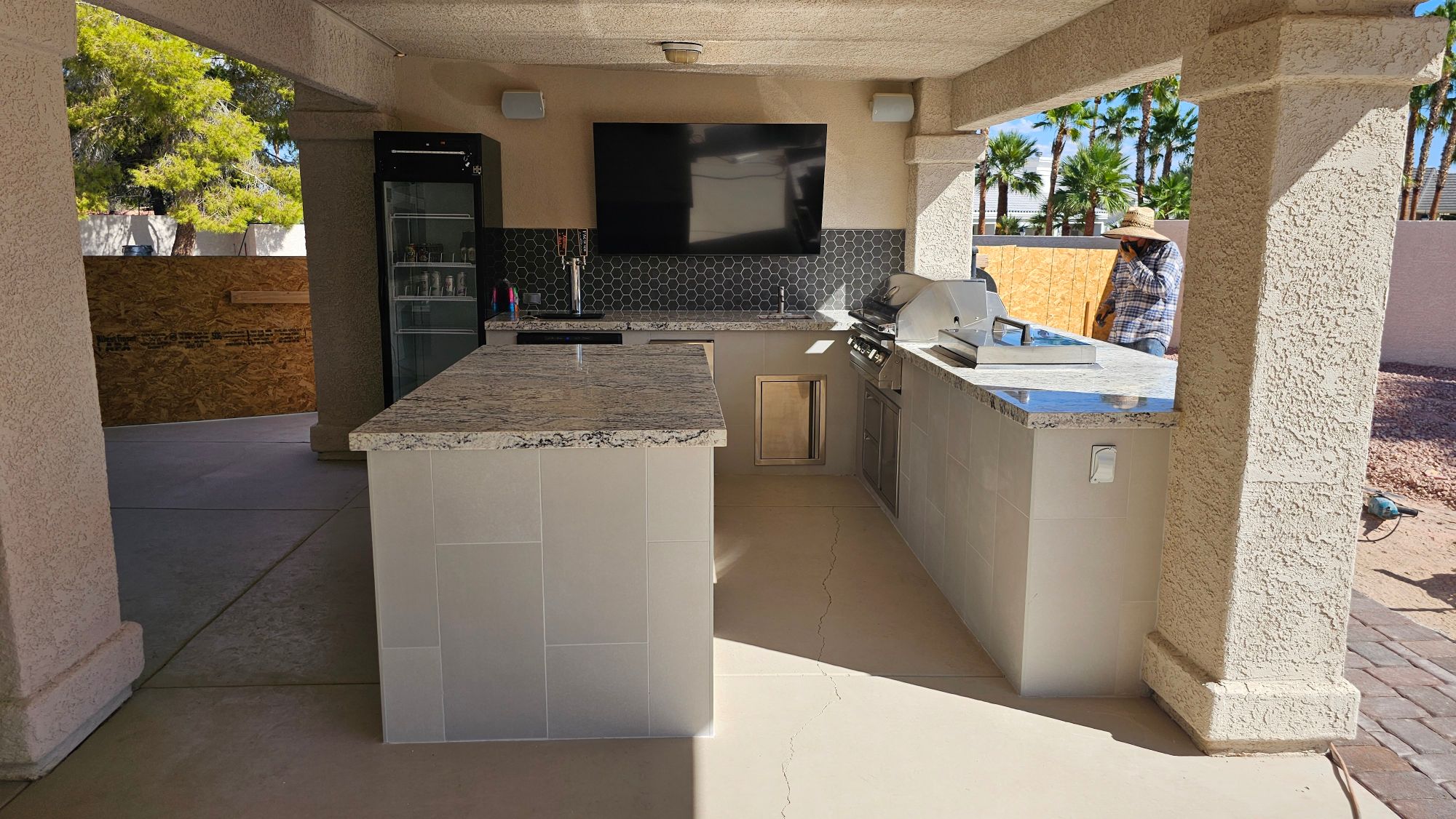 Finished L-shaped outdoor kitchen with granite island and bar seating in Lone Mountain Las Vegas